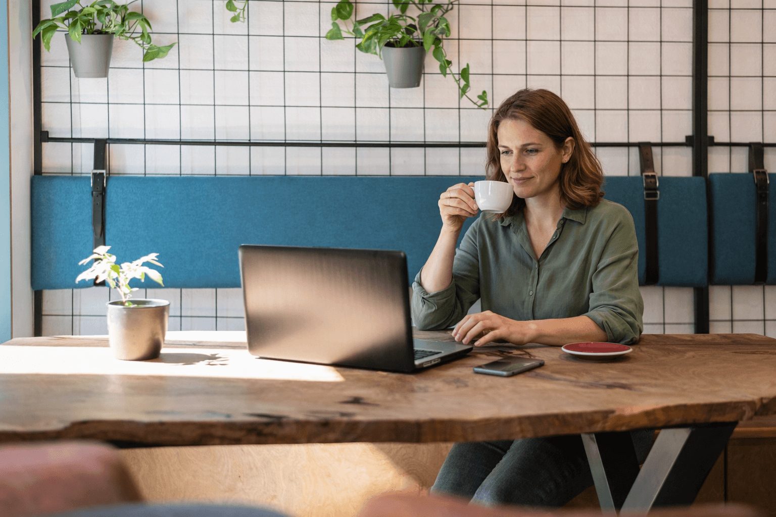Medewerker werkt met een kop koffie ontspannen op een laptop